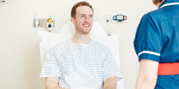 Male patient on hospital bed smiling
